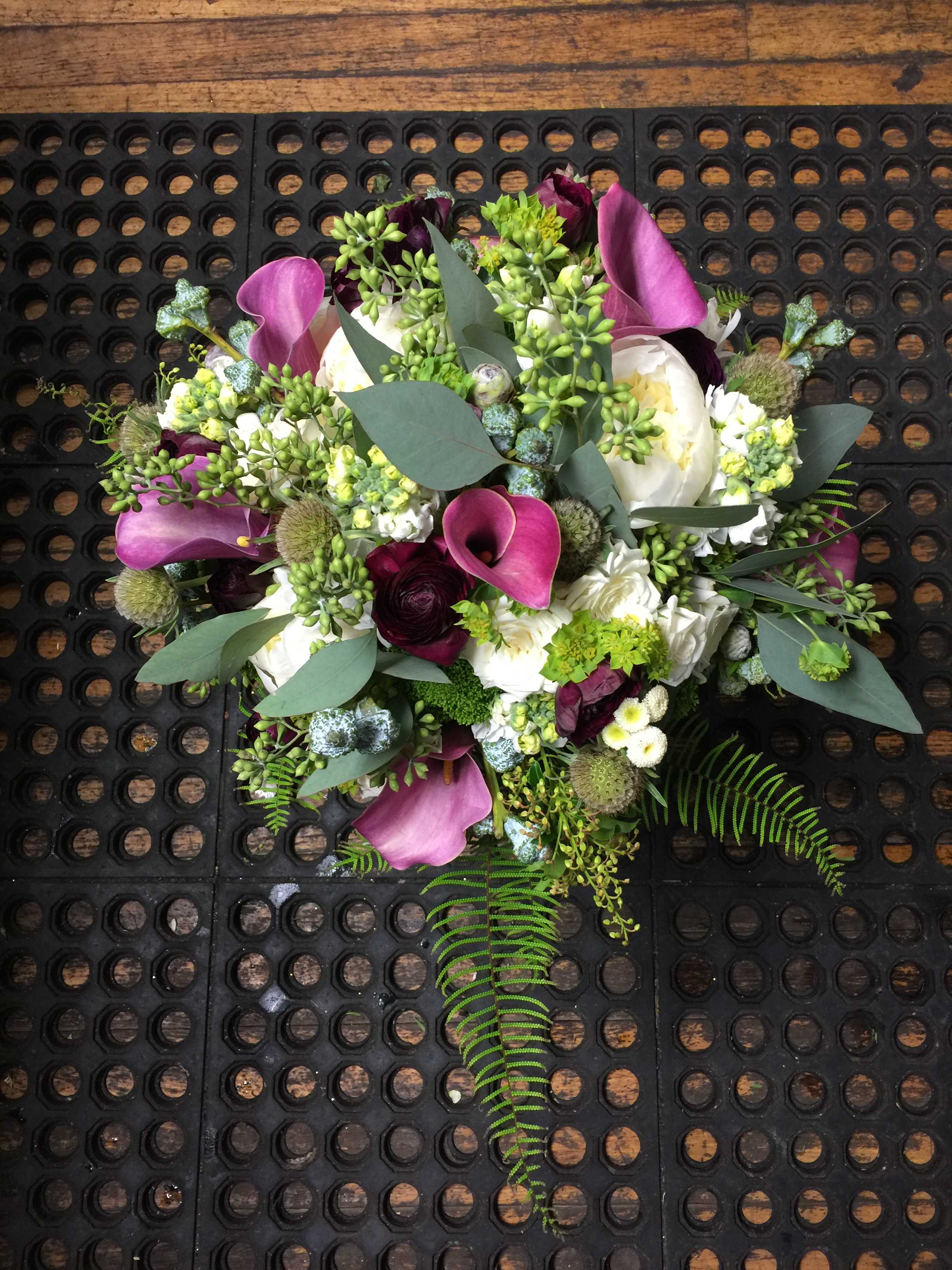 Bouquet of purple calla lilies and white blooms with greenery