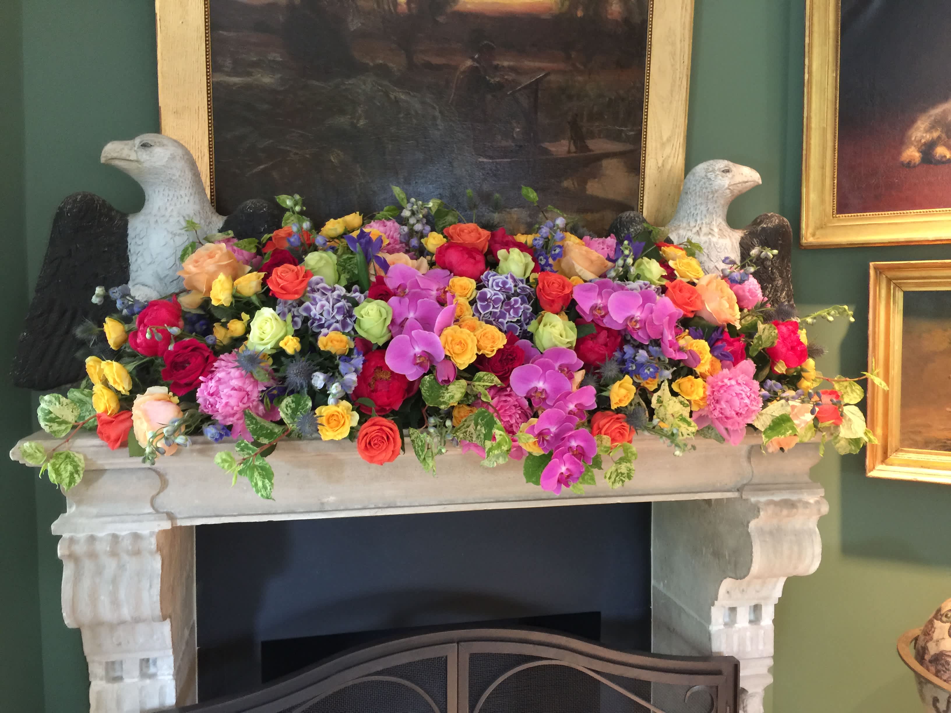 Colorful mixed floral arrangement on a mantel with two bird sculptures