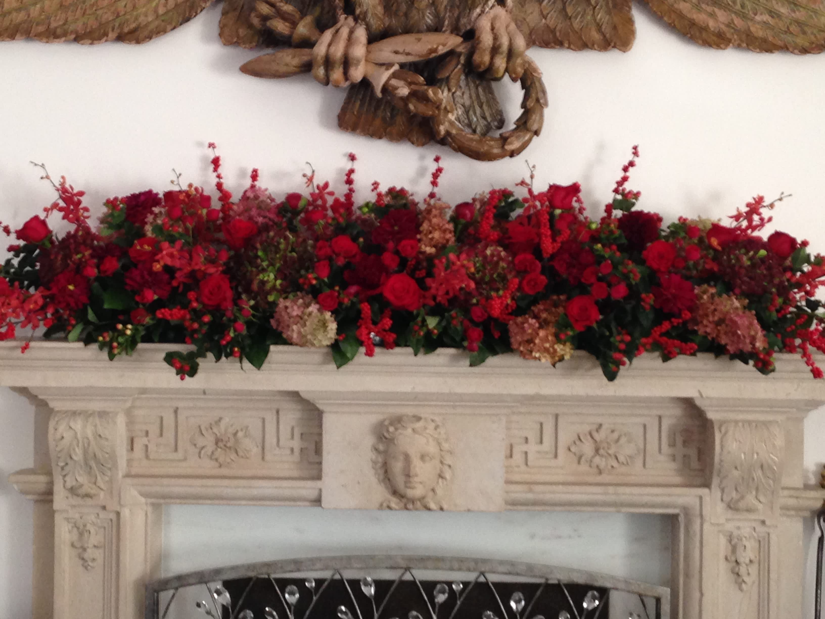 Long red floral arrangement displayed across a mantel