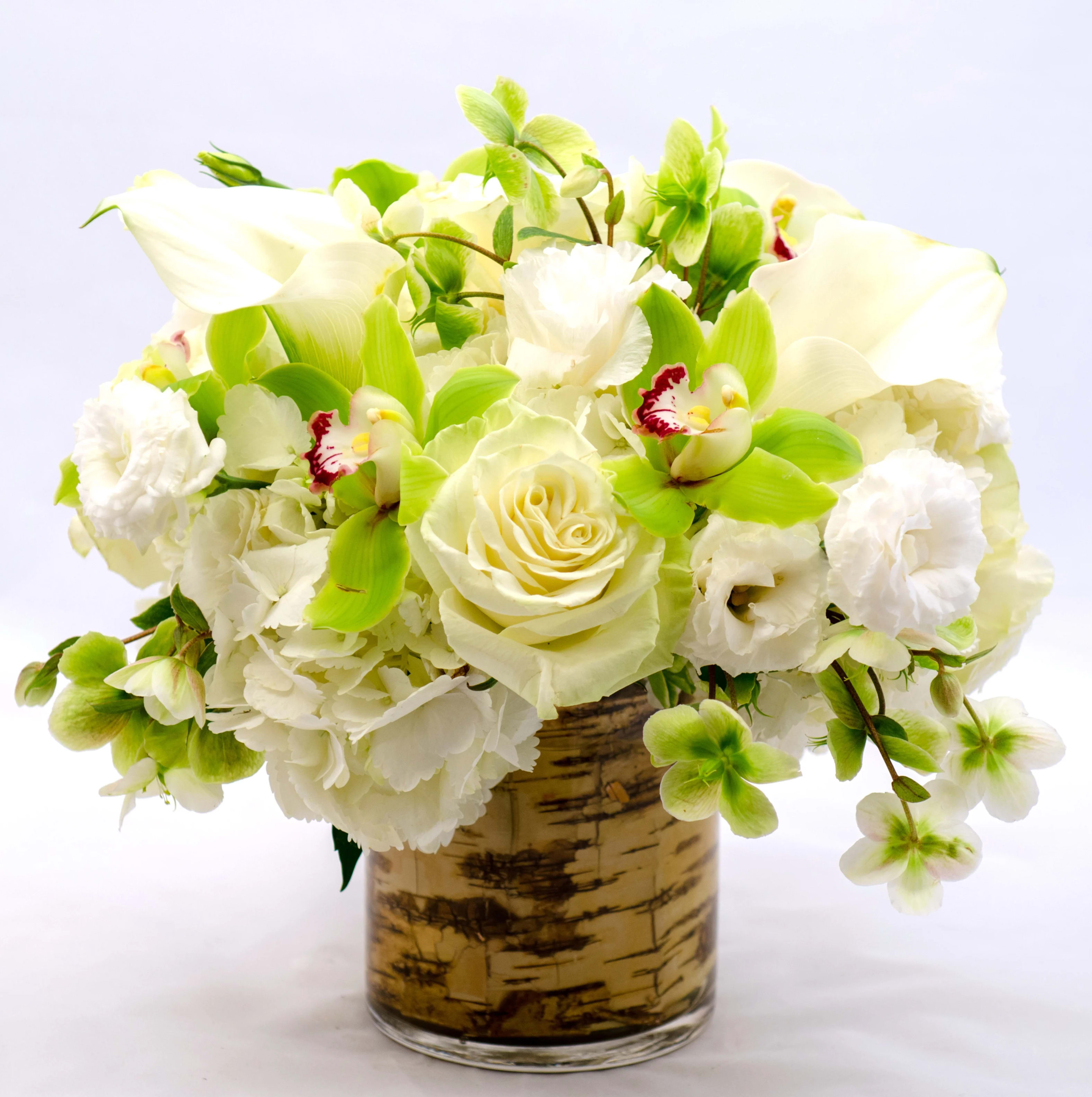 White and green floral arrangement in a birch-pattern vase