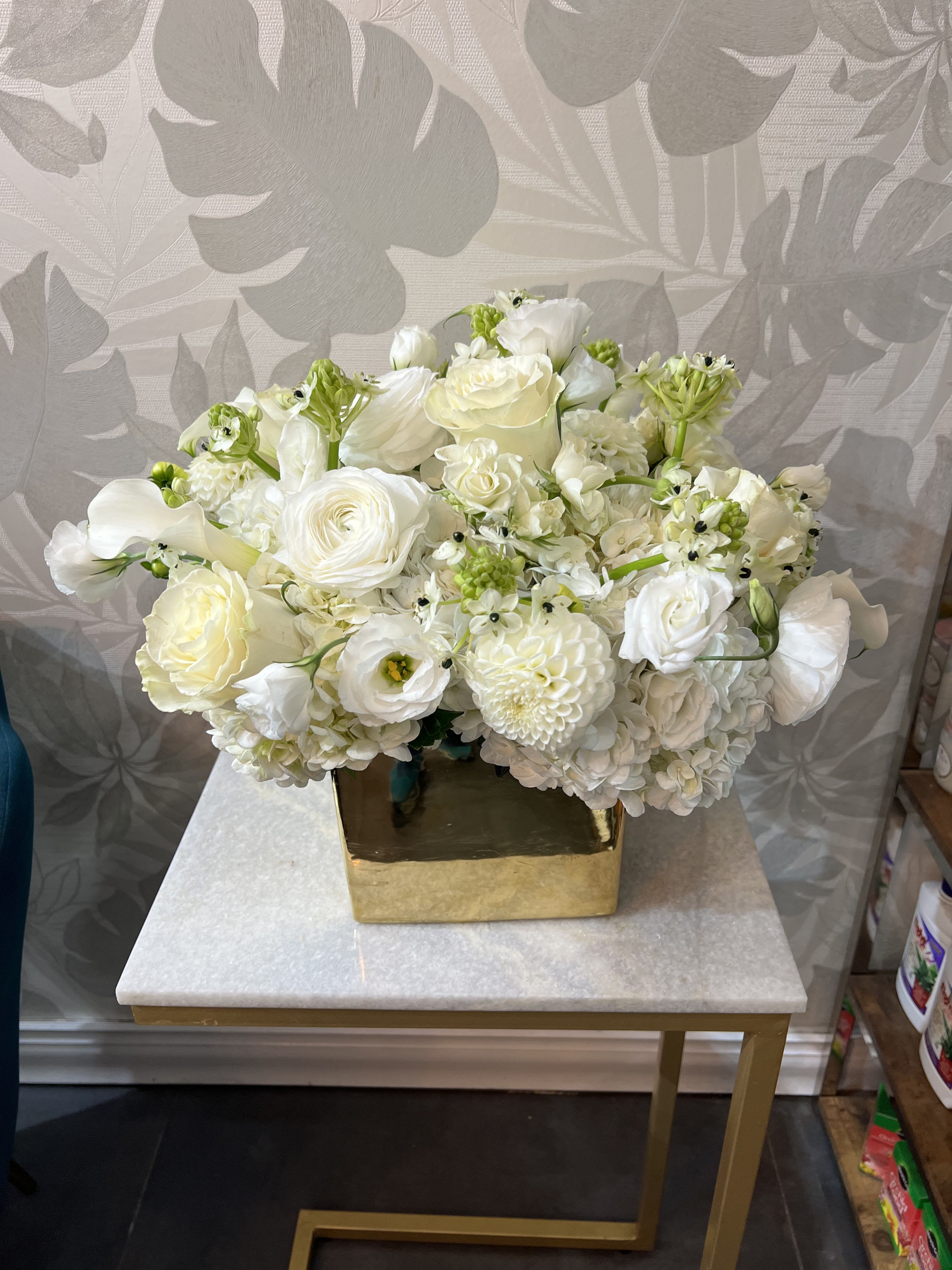 White floral arrangement in a gold square vase