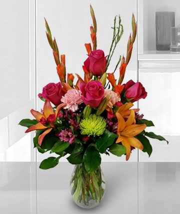 Bouquet of pink roses and orange lilies in a clear glass vase