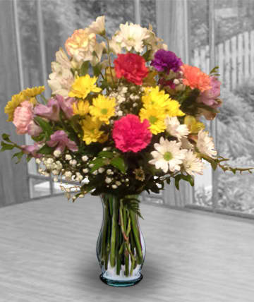 Mixed bouquet of colorful carnations and daisies in a glass vase