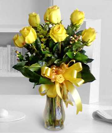 Yellow roses arranged in a glass vase with a yellow ribbon