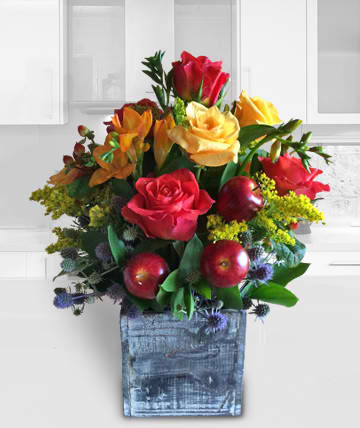 Mixed bouquet of red and yellow roses in a blue wooden container