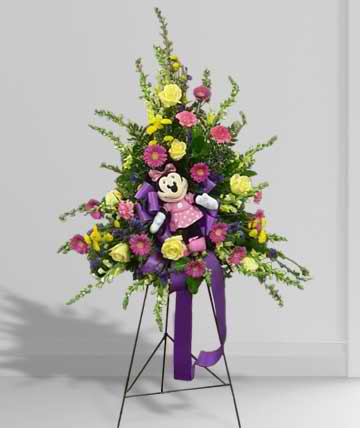 Tall floral standing spray with a teddy bear and purple ribbon