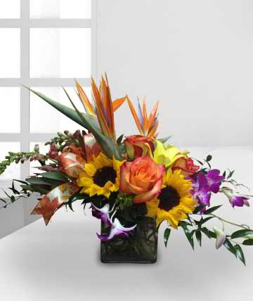 Tropical bouquet with sunflowers, roses, and orchids in a black vase
