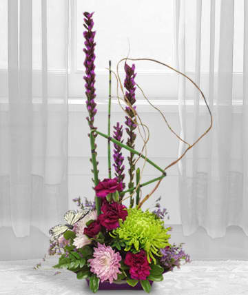 Tall floral arrangement with purple and pink blooms in a low container