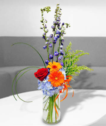 Mixed bouquet in a clear glass vase with red, orange, and blue flowers