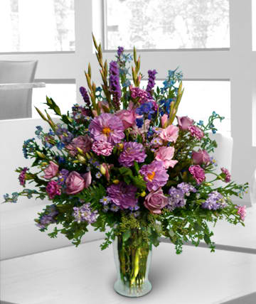 Large mixed purple and pink flower arrangement in a glass vase