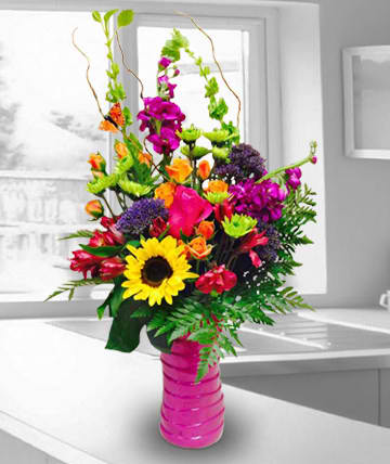 Bright mixed bouquet in a pink vase with a sunflower and orchids