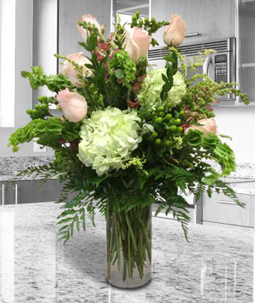 Tall bouquet of pale pink roses and white hydrangea in a glass vase