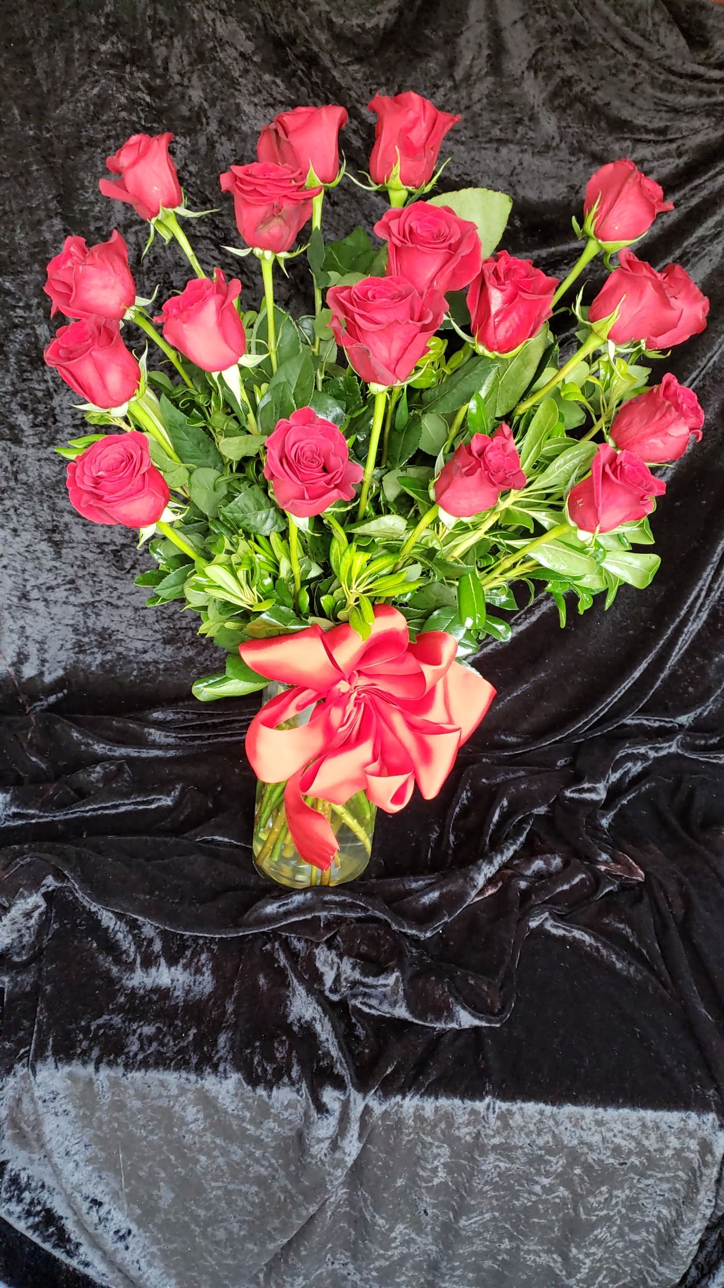 Bouquet of red roses in a glass vase with a red ribbon