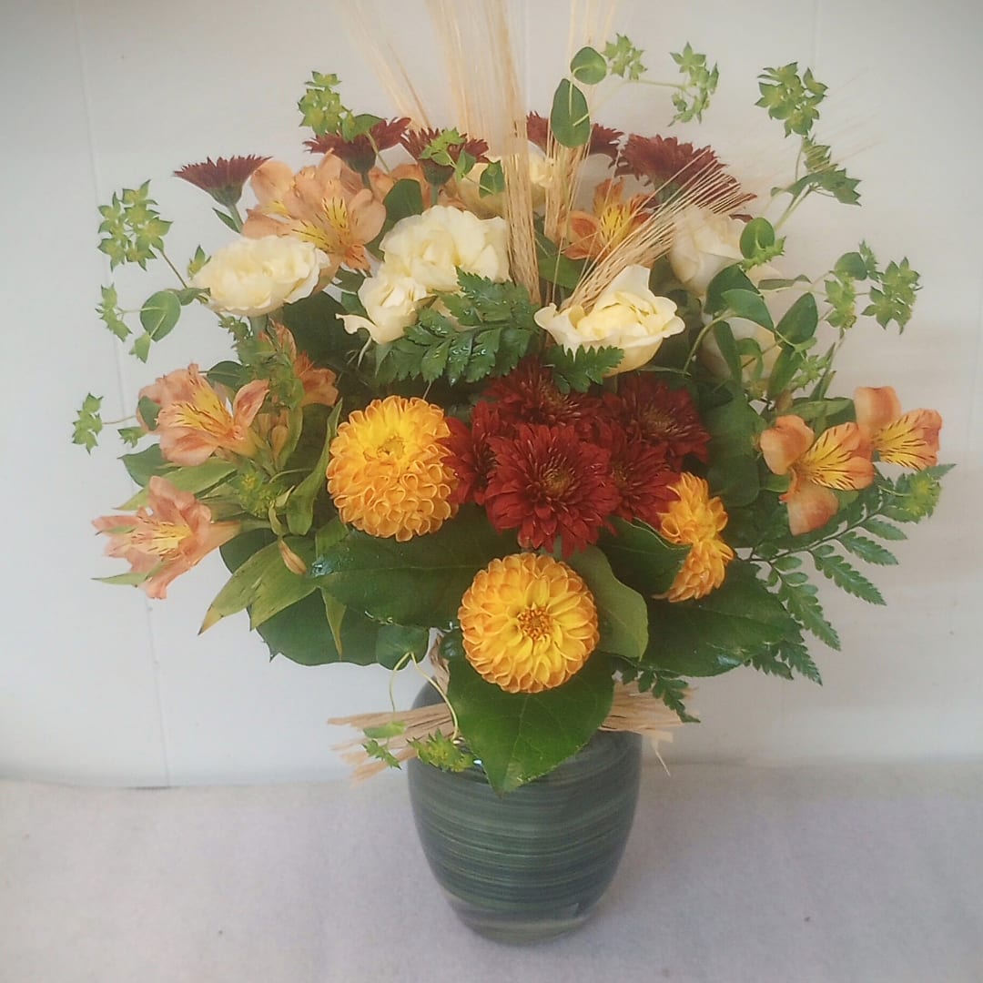 Mixed bouquet in a green vase with yellow, white, and red flowers