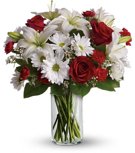 Red roses and white lilies with daisies in a clear glass vase
