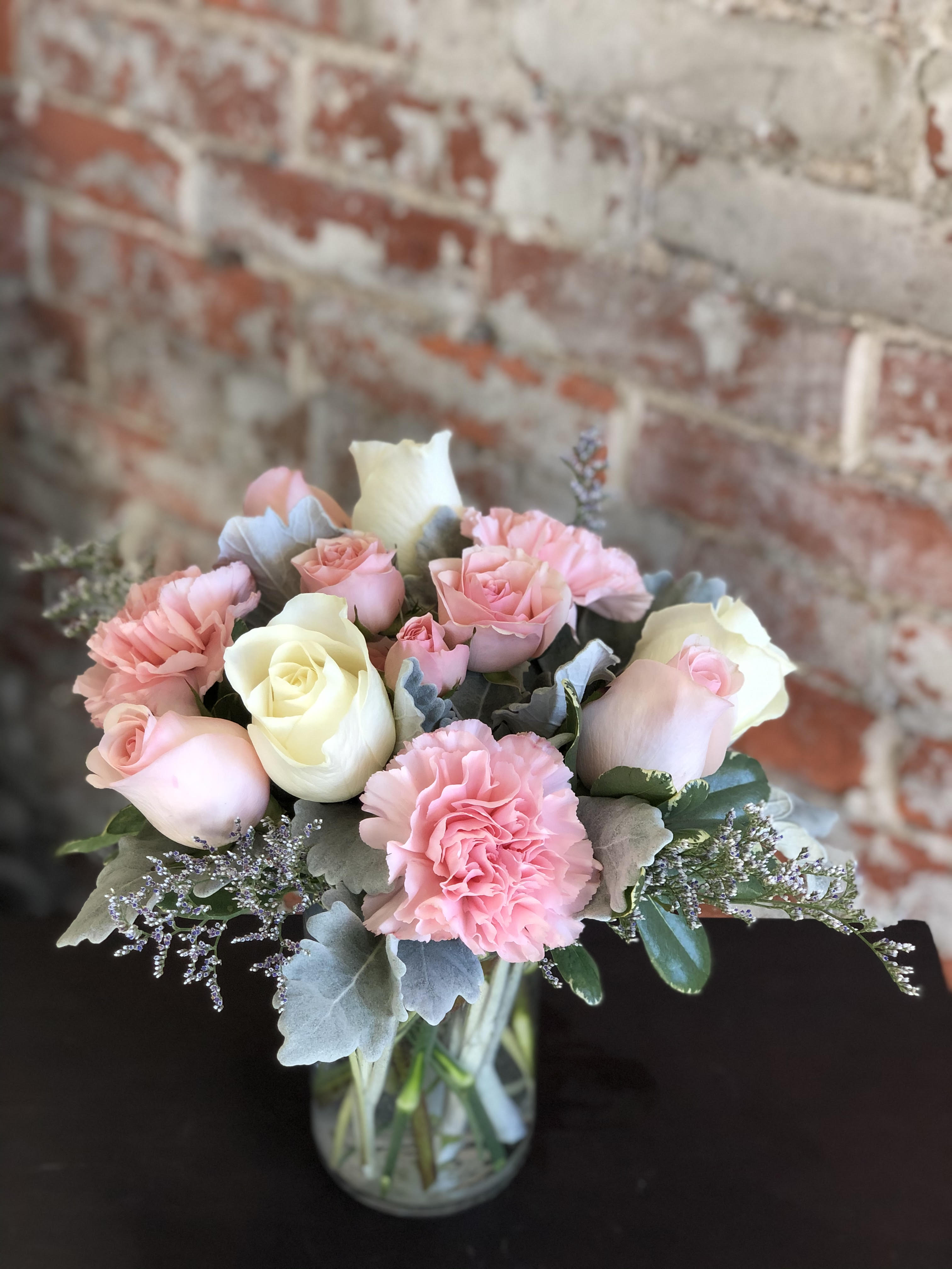 Pink and white roses with carnations in a glass vase