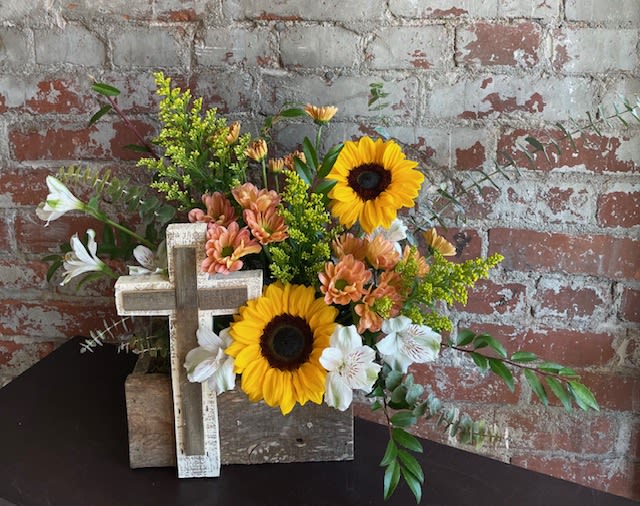 Sunflowers and white lilies arranged with a wooden cross