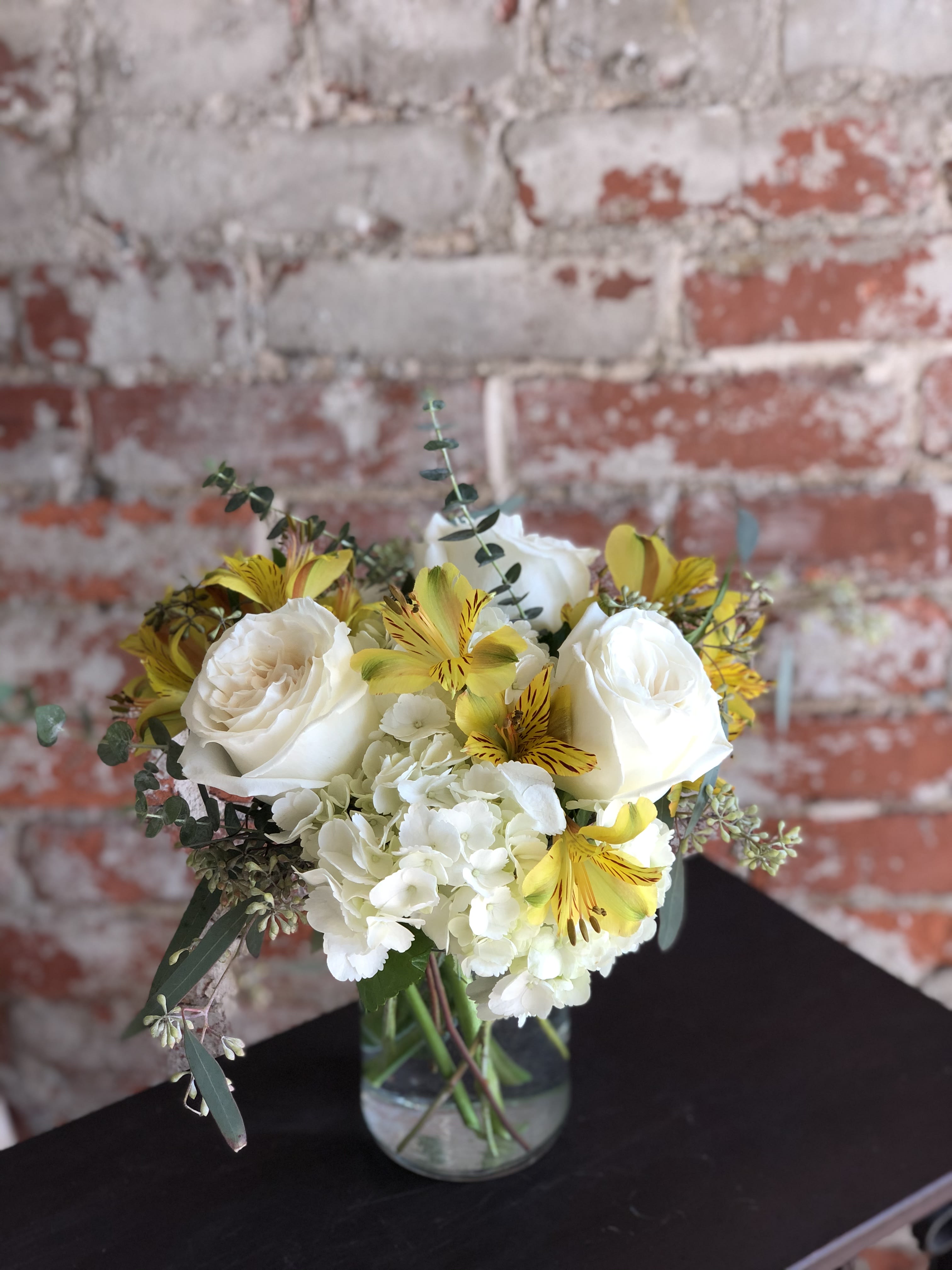 White roses and yellow alstroemeria in a glass vase
