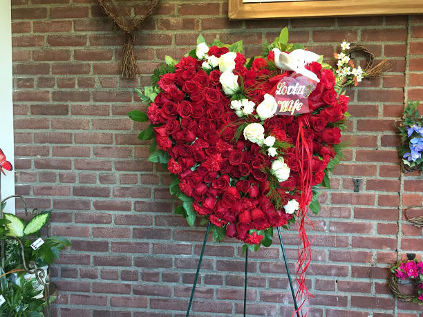 Heart-shaped red rose arrangement with white roses and a ribbon on an easel