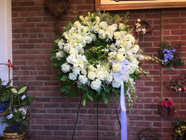 Large white floral wreath on a stand with a ribbon