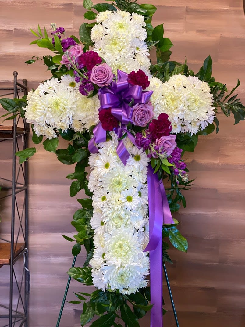 Cross-shaped floral spray with white chrysanthemums, purple roses, and a purple ribbon