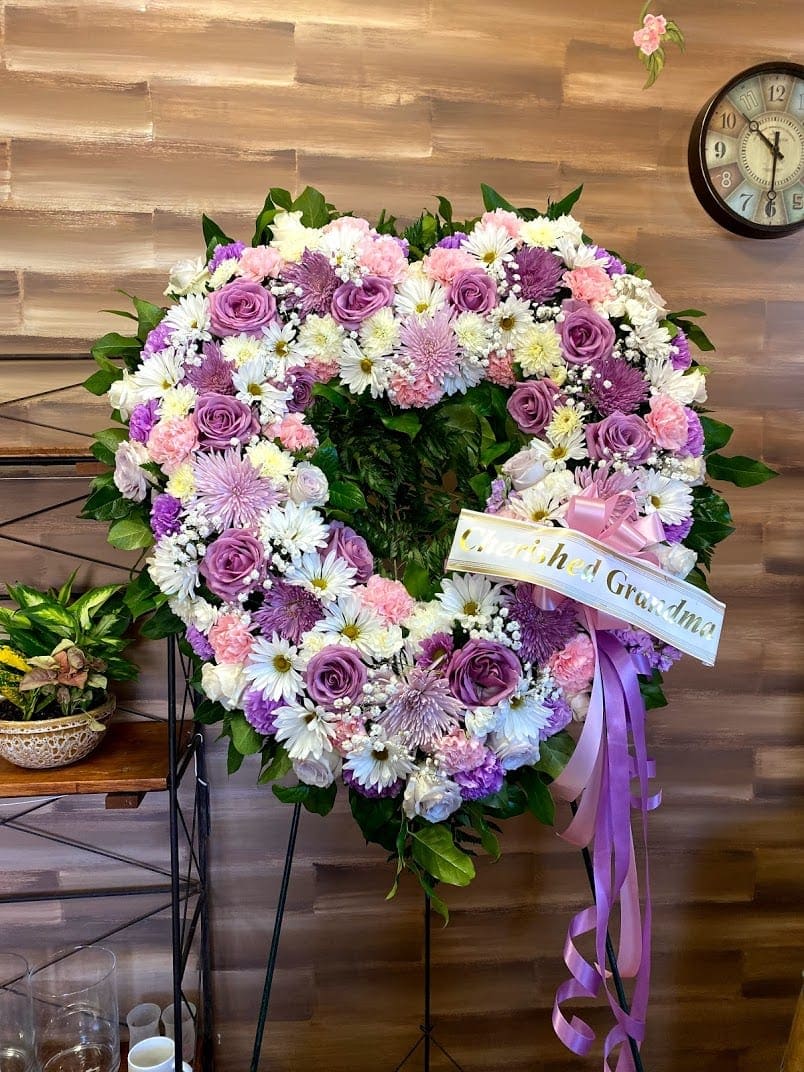Heart-shaped floral wreath with pink, purple, and white flowers on an easel