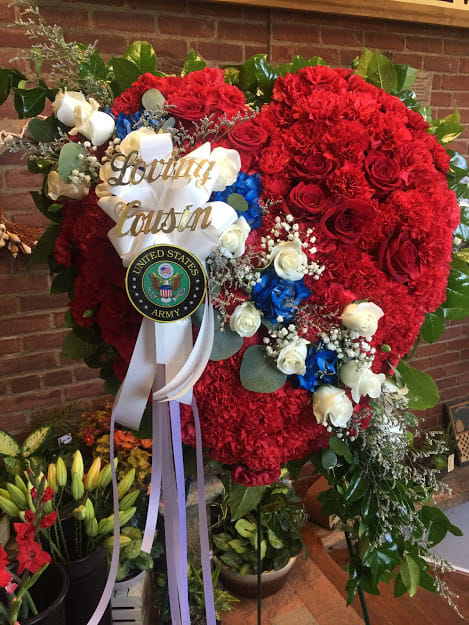 Large red floral standing spray with white and blue accents and a ribbon