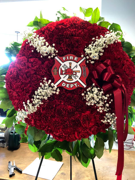 Red floral fire department wreath with white baby's breath and a ribbon