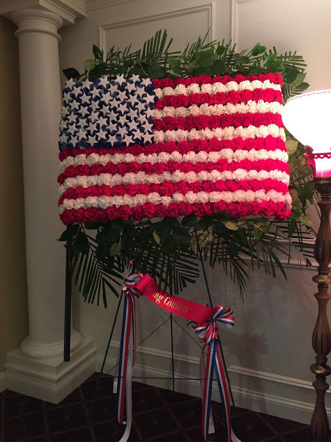Floral American flag display on an easel with red, white, and blue flowers