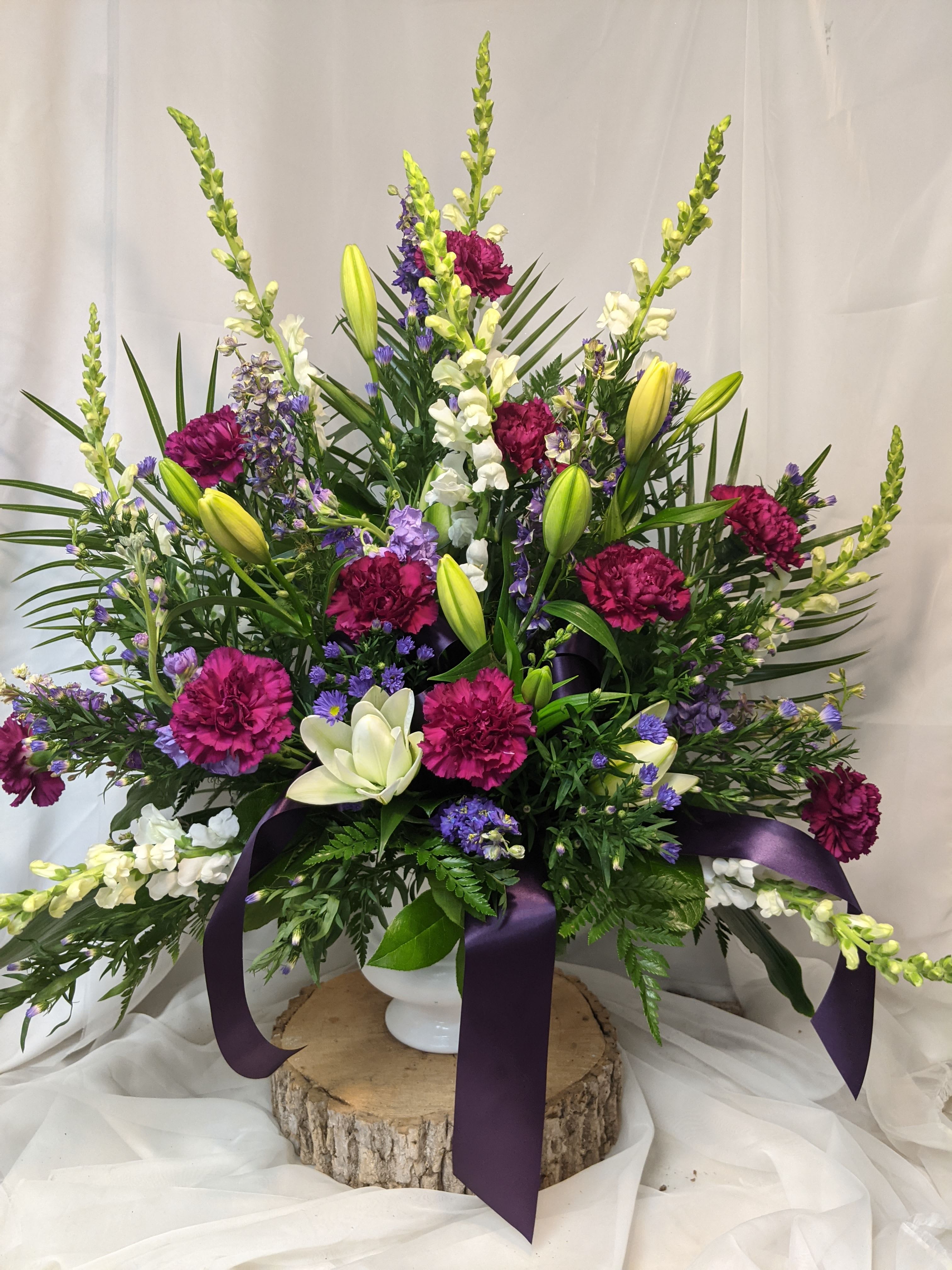 Large floral arrangement with purple and white flowers in a white vase