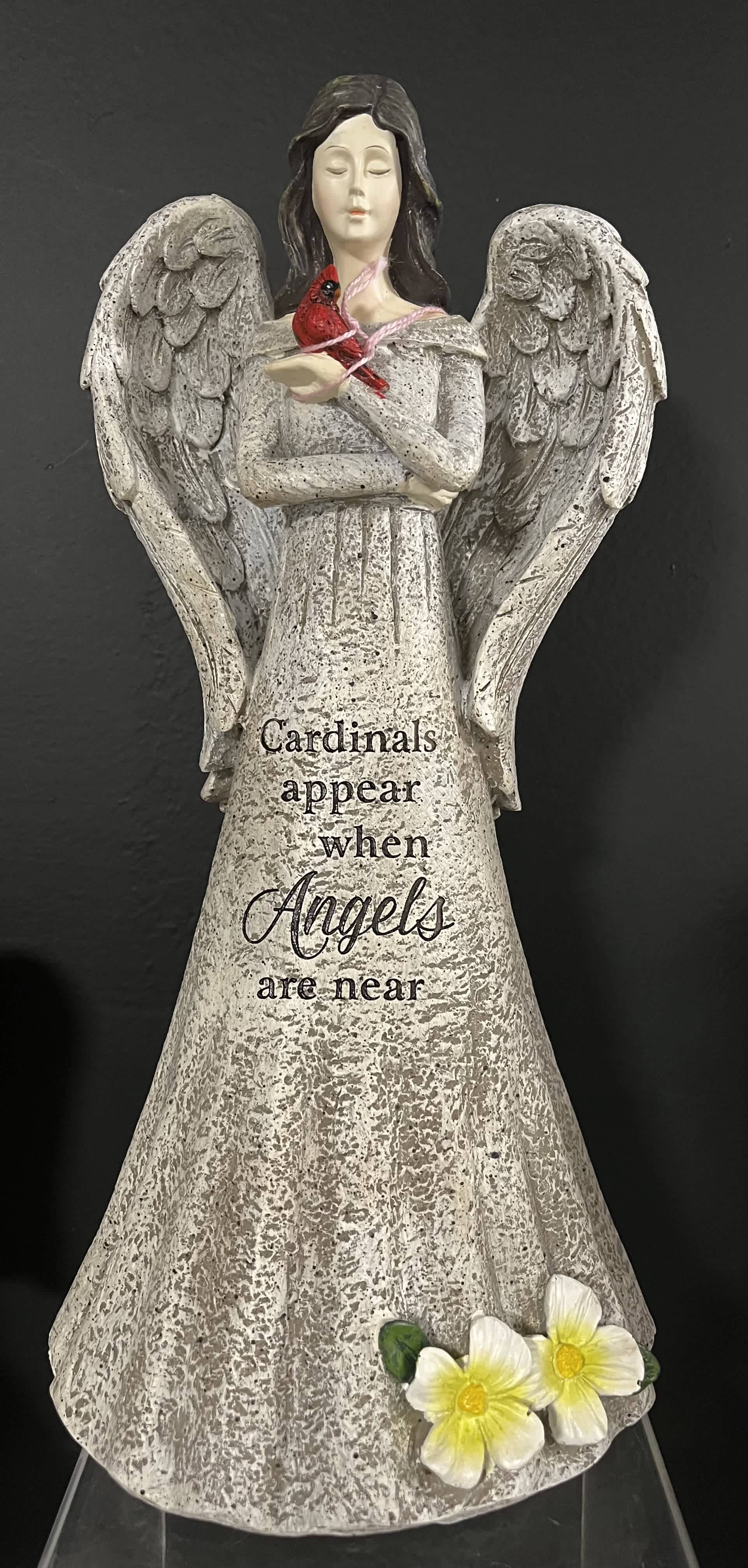 Angel figurine holding a red cardinal with yellow flowers at the base