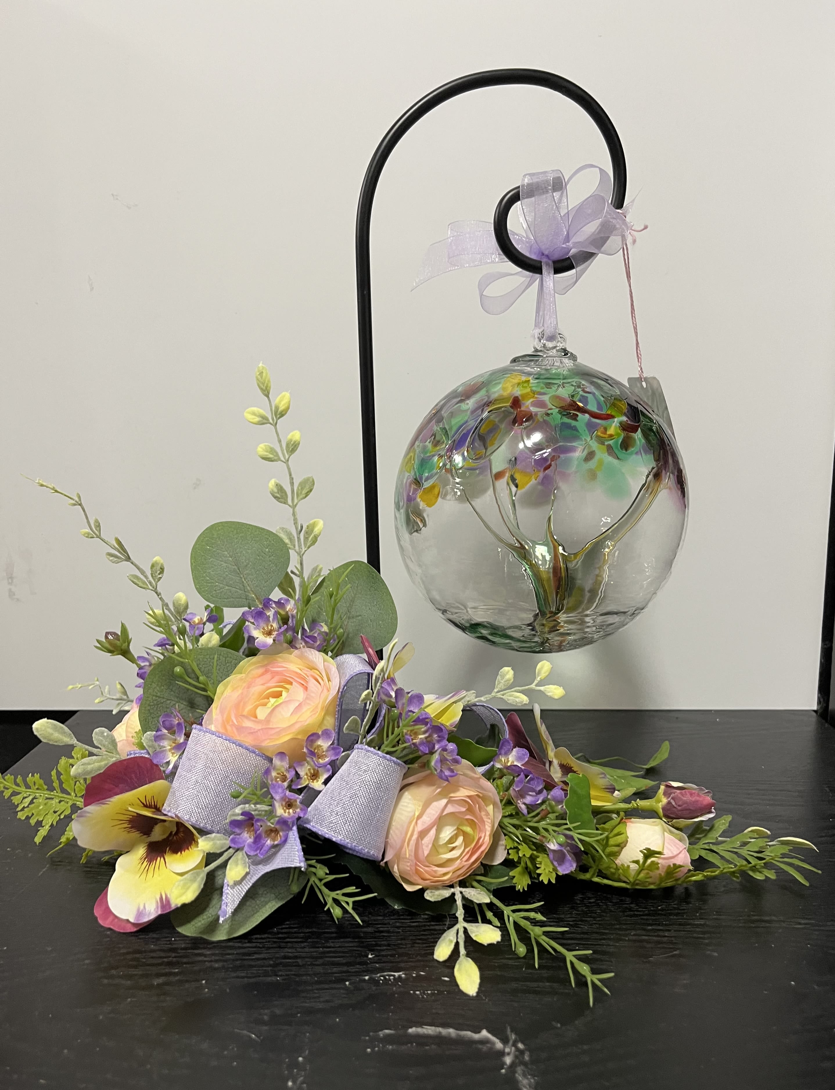Pastel floral arrangement with roses and purple accents beside a hanging glass ornament