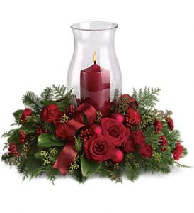 Holiday Glow Centerpiece - Glow ahead and send this spectacular centerpiece to anyone who's on your Christmas list this year. A glowing hurricane candle takes center stage but the surrounding festive touches make this arrangement radiate joy.  Beautiful red roses, spray roses and carnations, white asiatic lilies, festive Christmas greenery and ornaments plus an elegant hurricane candle make this divine Christmas décor.  Approximately 19" W x 15 1/2" H  Orientation: All-Around  As Shown : T115-3A Deluxe : T115-3B Premium : T115-3C