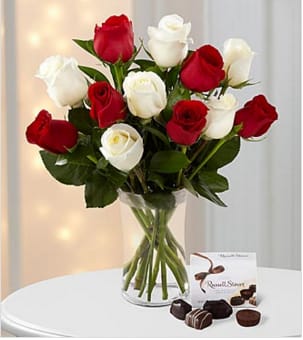Christmas Kindness Rose Bouquet - Picked fresh from the farm to help usher in the Christmas season, the Merry Everything Holiday Rose Bouquet is a fresh and inviting way to send your warmest season's greetings to any of the special people on your holiday shopping list! Hand gathered in select floral farms, this bouquet of roses, in the shades of white and red, has been picked fresh for you to help bring untapped merriment to their yuletide celebration. This bouquet includes: a dozen roses in the shades of both red and white, accented with lush greens and a 4-piece box of Russell Stover® Chocolates. Presented with a classic clear glass vase. Approximately 14"H x 12"W. Your purchase includes a complimentary personalized gift message.