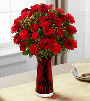 The FTD® Spirit of the Season™ Bouquet - The FTD® Spirit of the Season™ Bouquet bursts with beauty and cheer to dazzle your special recipient with its holiday beauty. Brilliant red spray roses and mini carnations are brought together with burgundy mini carnations, red hypericum berries and assorted holiday greens in a clear glass vase accented with a thick red designer ribbon to create a special sentiment of seasonal wishes and caring kindness. BETTER bouquet is approximately 15"H x 10"W. Your purchase includes a complimentary personalized gift message.