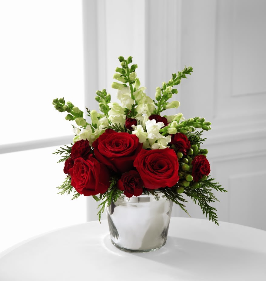 The FTD® Season's Sparkle™ Bouquet - The FTD® Season's Sparkle™ Bouquet is set to dazzle your special recipient this holiday season. Rich red roses are offset by white snapdragon stems, burgundy mini carnations, green hypericum berries and assorted holiday greens beautifully arranged in a silver metallic round glass vase to create an incredible gift of Christmas elegance that spreads the joy of this exciting season.