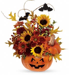 Teleflora's Trick &amp; Treat Bouquet - Red spray roses, bright yellow sunflowers, orange daisy spray chrysanthemums and curly willow make this bouquet so beautiful, it's scary! It's accented by two black bats and nestled inside our popular ceramic Trick &amp; Treat Pumpkin, complete with a jack-o-lantern face. Happy Halloween!