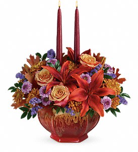 Teleflora's Autumn Ablaze Centerpiece - Celebrate the season with this elegant autumnal centerpiece, featuring fall's favorite hues and glowing taper candles. Lush orange roses and asiatic lilies are arranged in a magnificent, multi-glazed stoneware bowl that's hand-glazed and food-safe for years of beauty and enjoyment!  Container is discontinued, will sub in a container as similar as possible