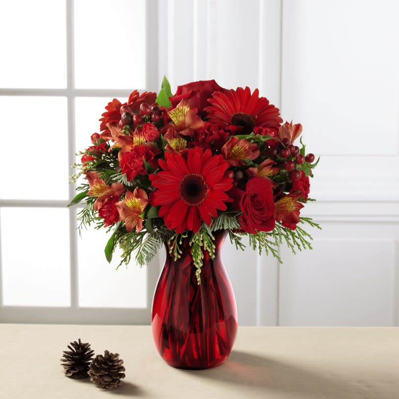 The FTD Spirit of the Season Bouquet - A sensational splash of red to celebrate the Christmas season in style, this impressive flower bouquet is ready to get you noticed. Red roses, gerbera daisies, Peruvian Lilies, mini carnations, and hypericum berries are accented with an assortment of fresh Christmas greens to create a joyful holiday look. Presented in a ruby red glass vase, this holiday flower arrangement is a heartfelt way for you to send your warmest season's greetings. 