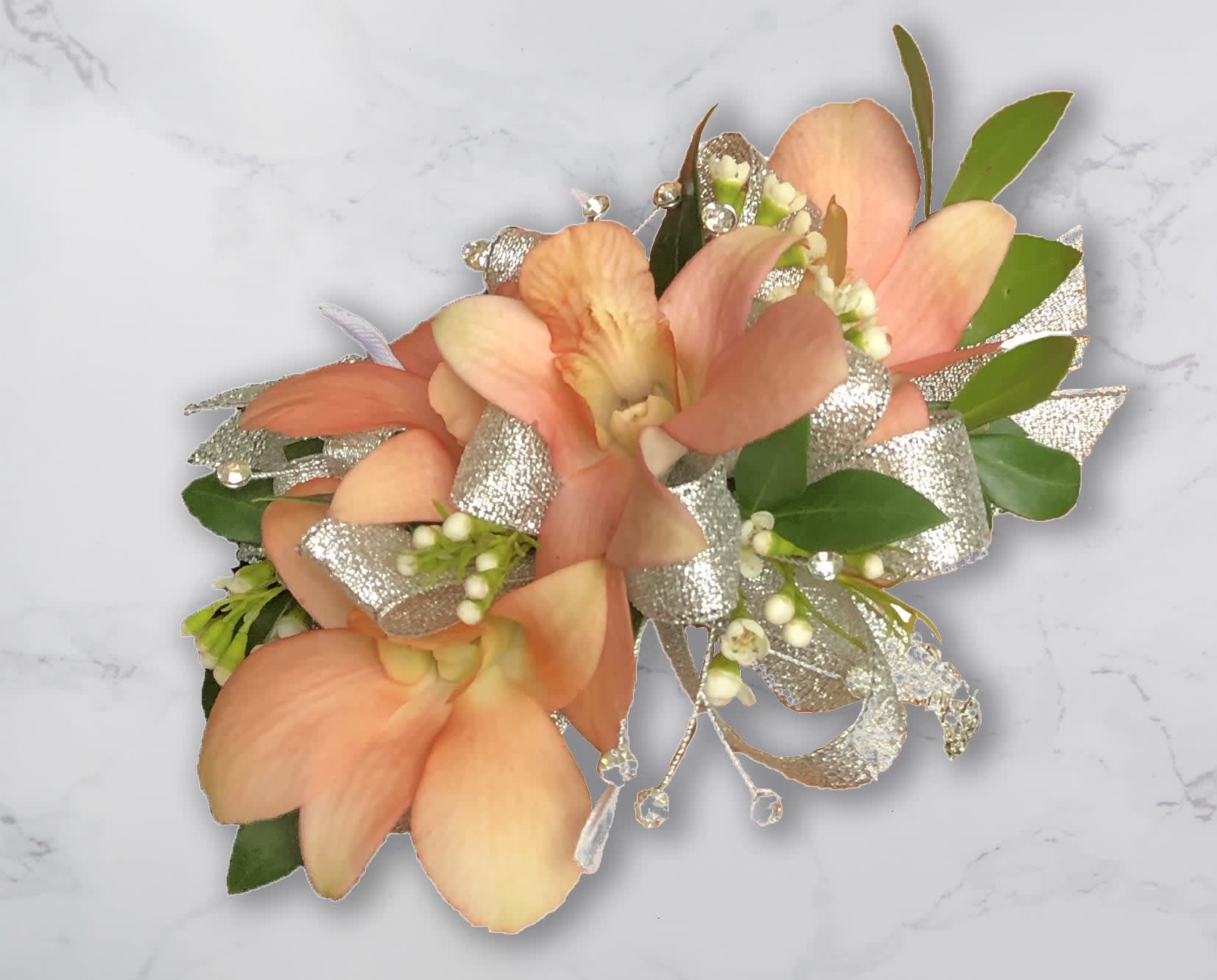 Peach orchid corsage with silver ribbon and green leaves
