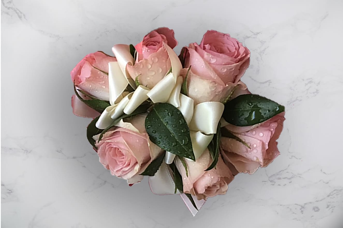 Pink rose bouquet with white ribbon on a light surface
