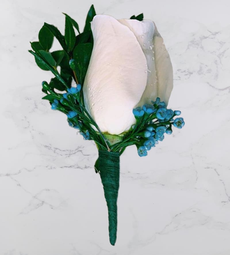 White rose boutonniere with blue accents and green leaves