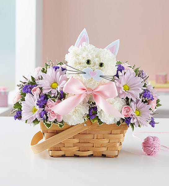 White cat-shaped flower arrangement in a wicker basket with pink and purple flowers