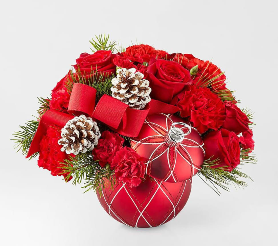 Red roses and carnations arranged with pinecones in a red ornament vase