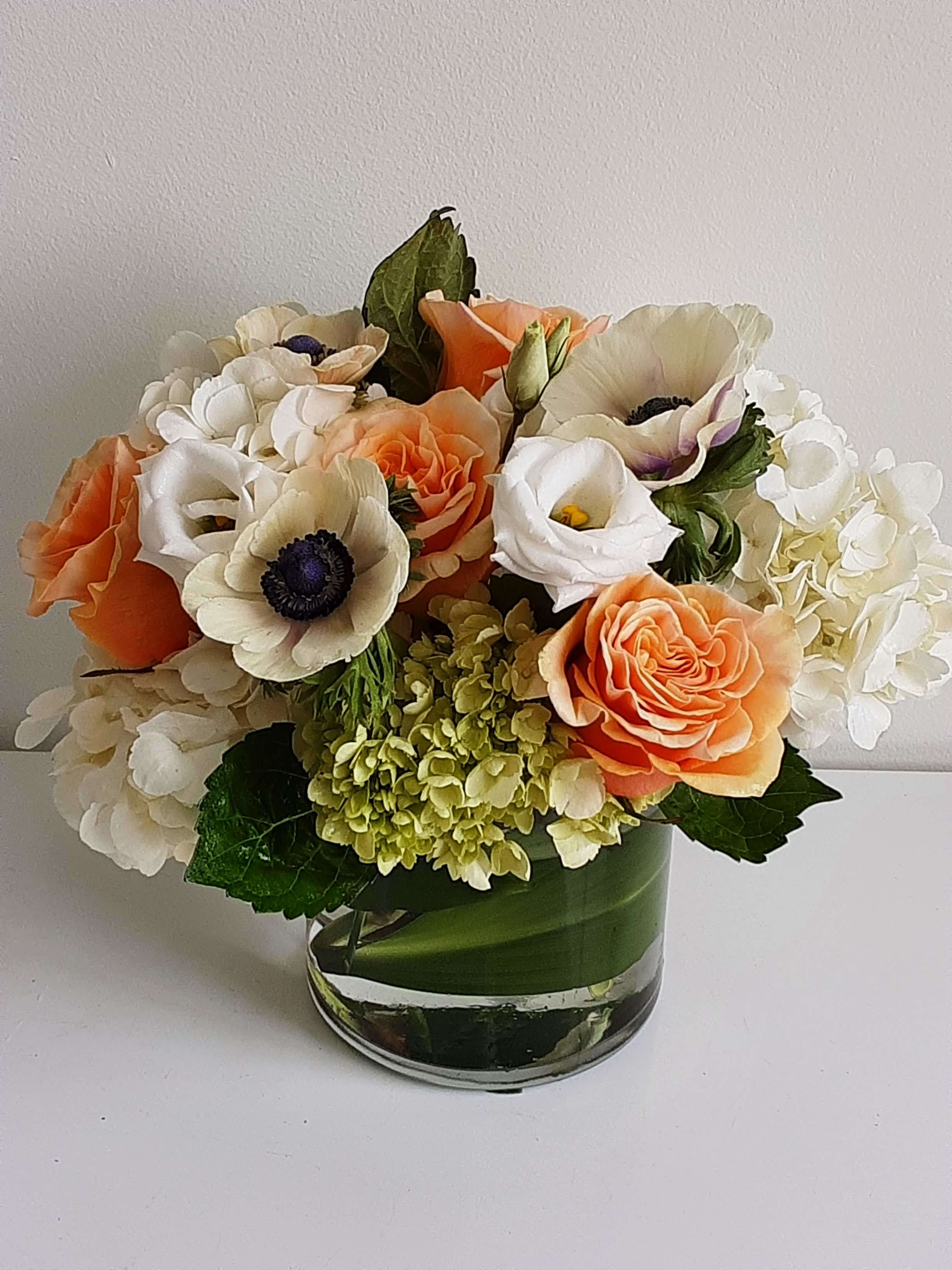 Bouquet of peach, white, and cream flowers in a glass vase