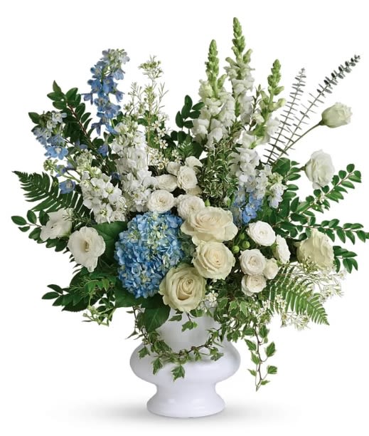 White and blue floral arrangement in a white pedestal vase