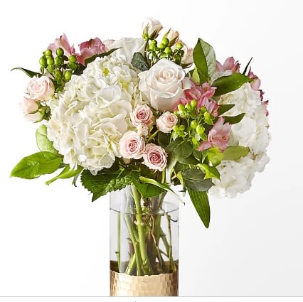 White hydrangeas and pale pink roses in a clear glass vase