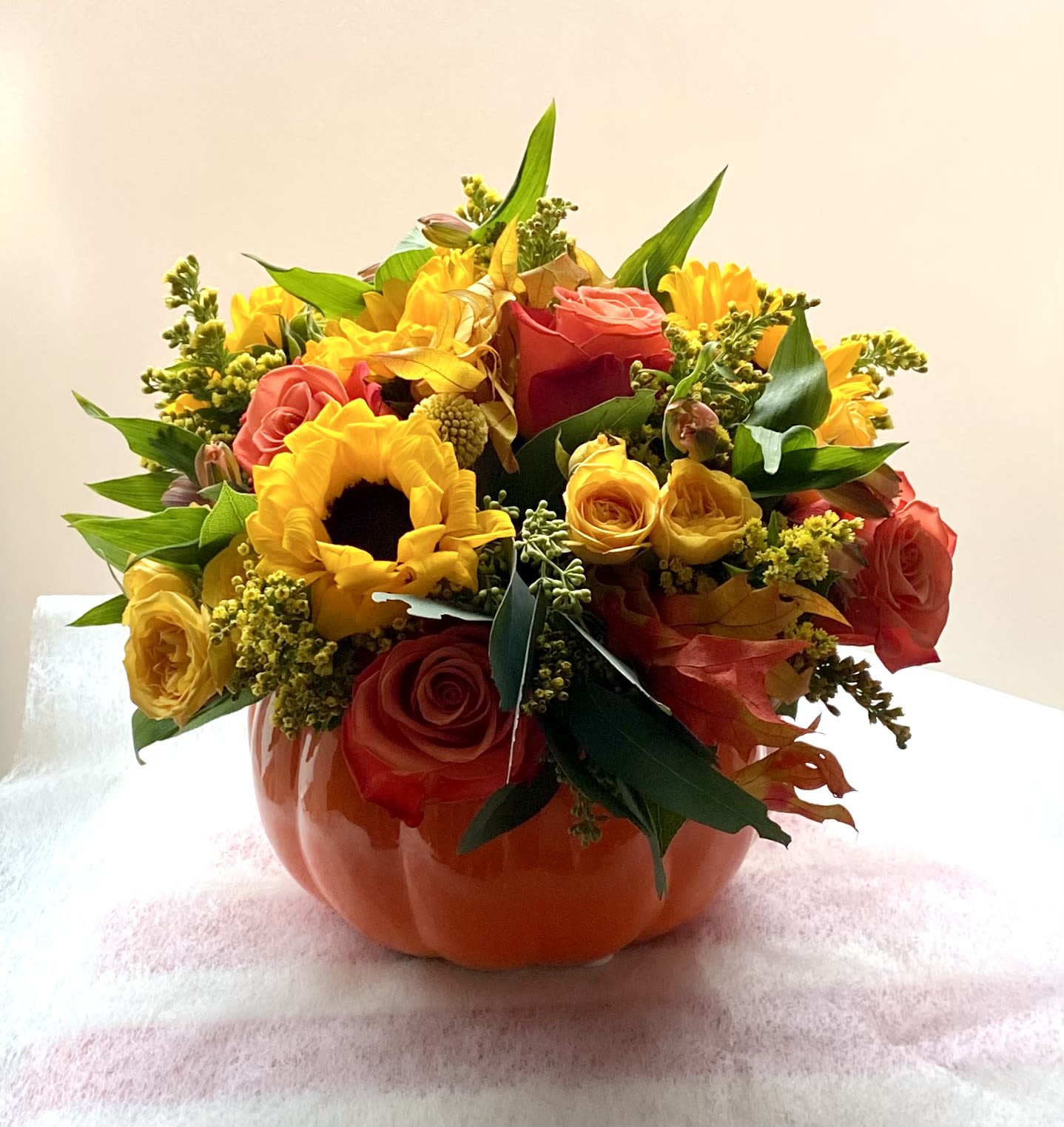 Mixed bouquet of roses and sunflowers in an orange vase