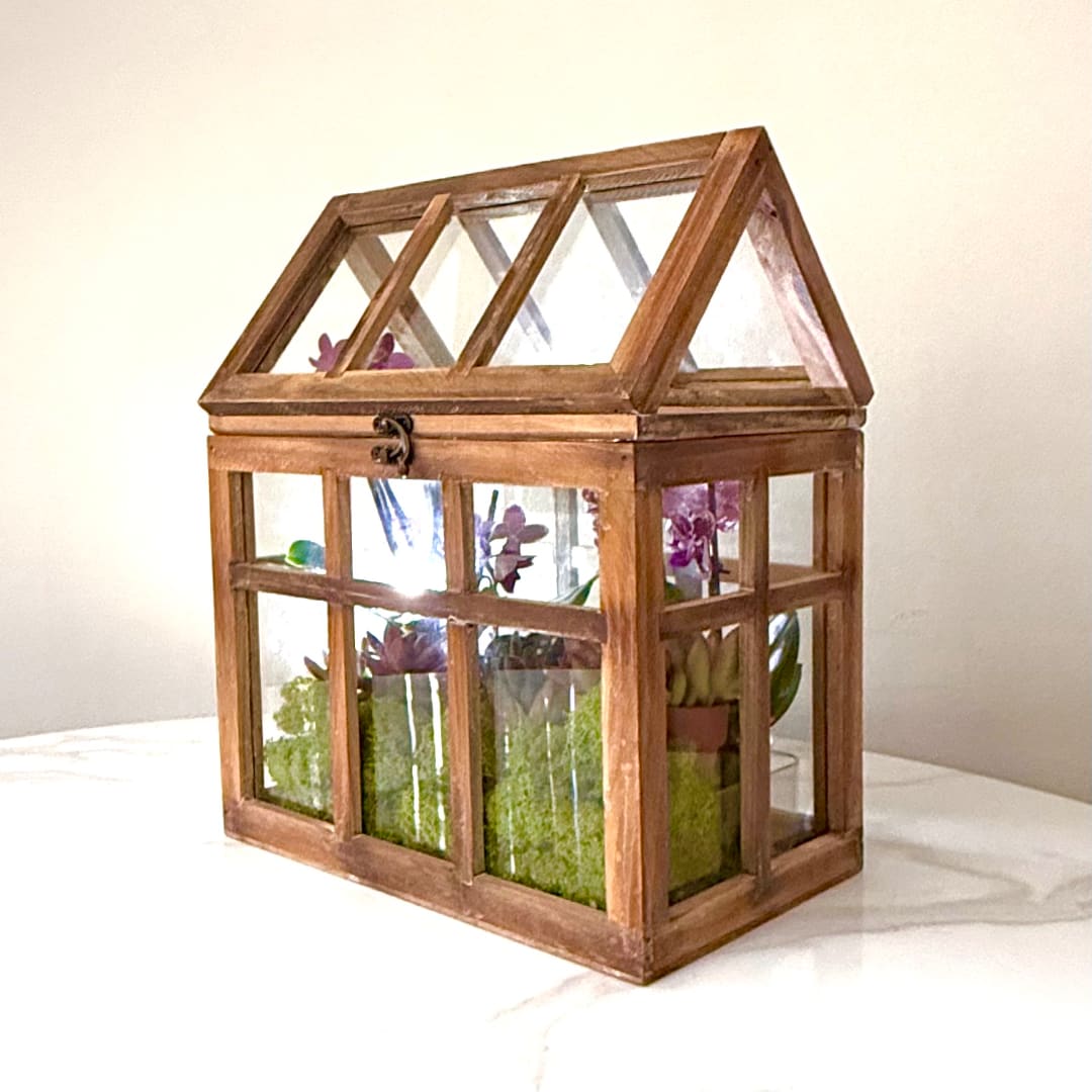 Wooden terrarium with purple orchids and succulents inside