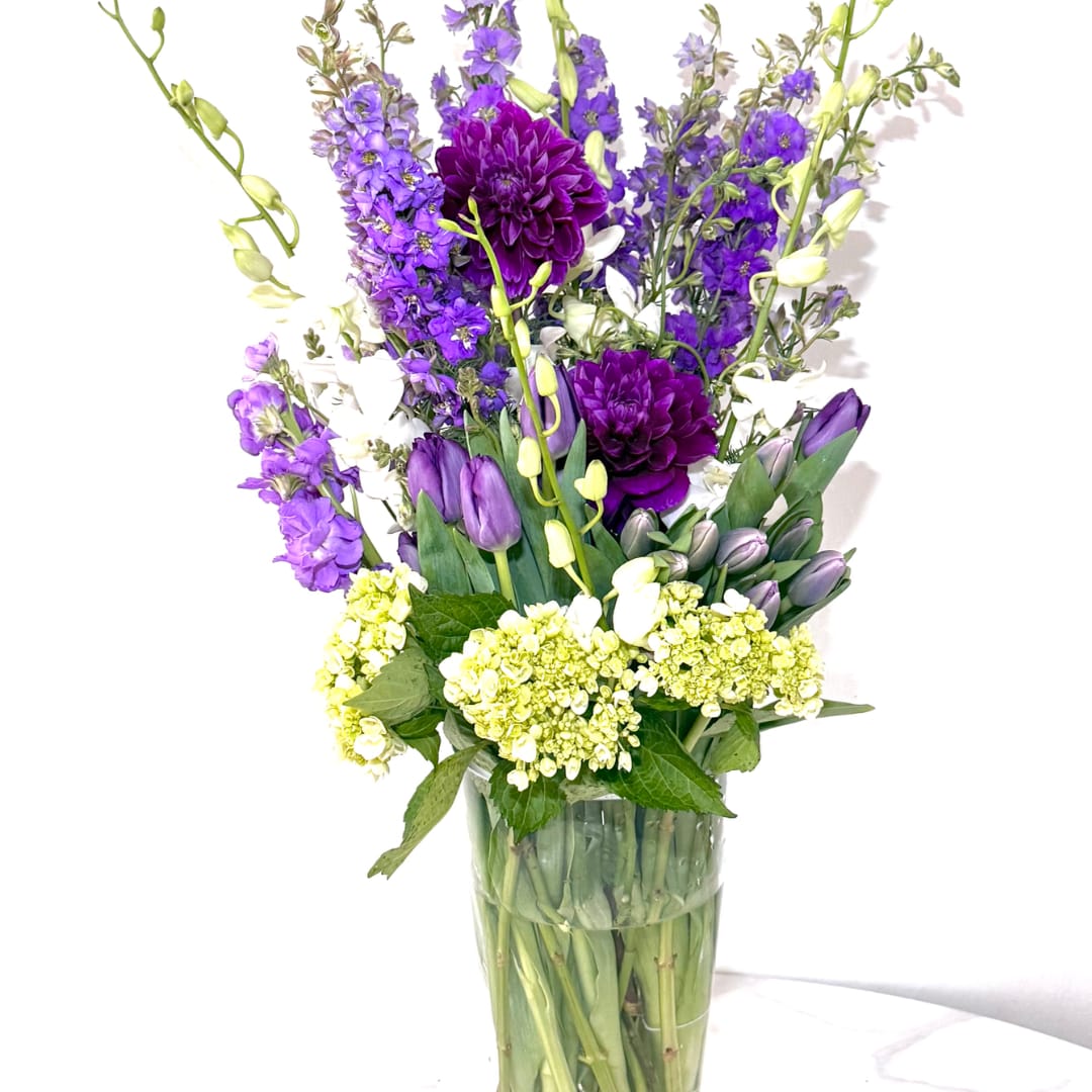 Purple and white mixed bouquet in a clear glass vase